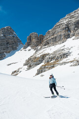 Fototapeta na wymiar Female skier on downhill slope surrounded with spectacular mountain ridge.