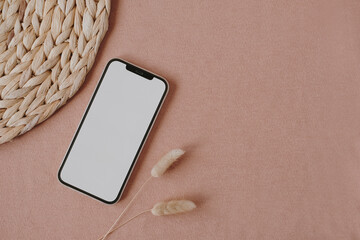 Blank screen mobile phone with copy space on neutral pastel coral background. Flat lay, top view....