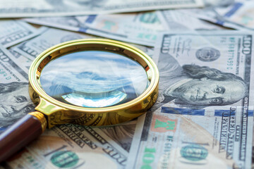one hundred dollars. a magnifying glass in a gold frame. close-up