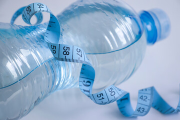 Bottle of water centimeter tape on a light background