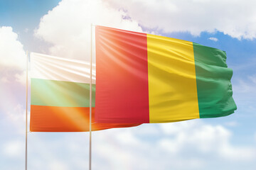 Sunny blue sky and flags of guinea and bulgaria
