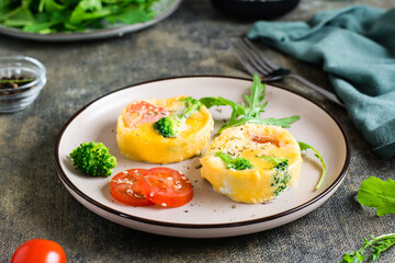 Ready to eat egg, broccoli and tomato frittata on a plate on the table. Homemade breakfast