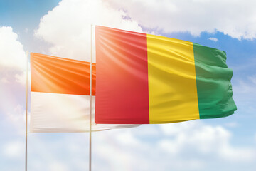 Sunny blue sky and flags of guinea and indonesia