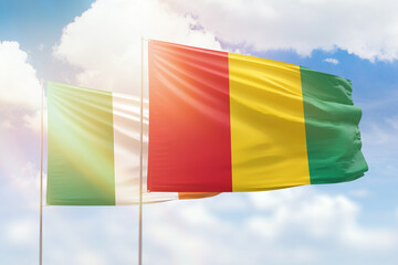 Sunny blue sky and flags of guinea and ireland