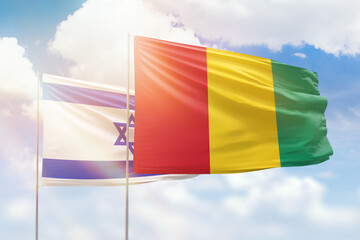 Sunny blue sky and flags of guinea and israel