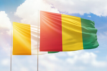 Sunny blue sky and flags of guinea and ivory coast