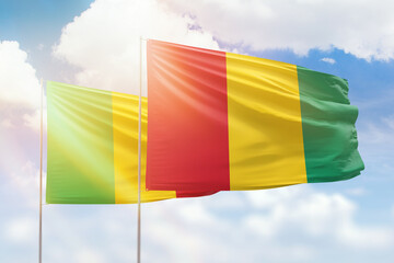 Sunny blue sky and flags of guinea and mali