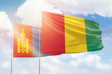 Sunny blue sky and flags of guinea and mongolia
