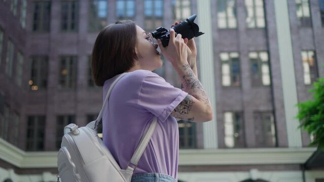 Young Girl With Tattoos Takes Pictures of Modern Building in City Center