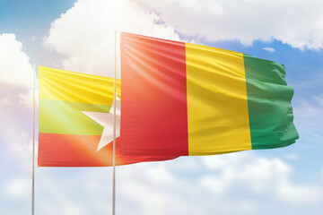 Sunny blue sky and flags of guinea and myanmar