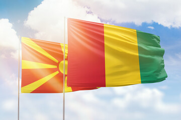 Sunny blue sky and flags of guinea and north macedonia