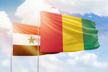 Sunny blue sky and flags of guinea and syria
