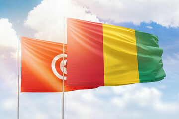 Sunny blue sky and flags of guinea and tunisia