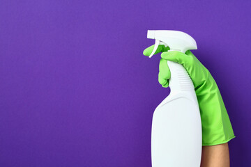 Female hand with white spray bottle mockup over purple background. House cleaning service and...