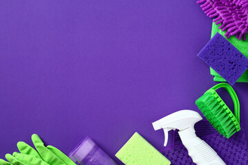 Cleaning products on purple background. House cleaning service and housekeeping concept. Flat lay, top view.