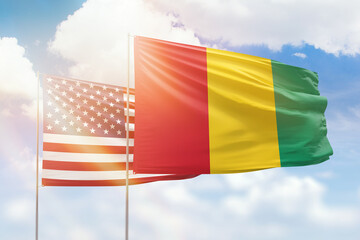 Sunny blue sky and flags of guinea and usa