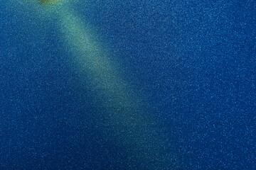 On a blue background in fine white grain a yellow diagonal beam of light