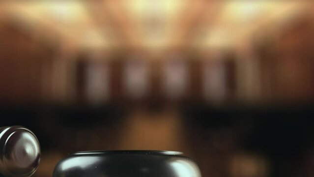 Judge is hitting gavel off a block in courtroom. Gavel is being struck to decide an auction or guilty verdict in court