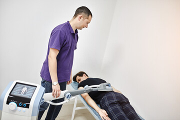 Electromagnetic therapy of the back. Physiotherapist doctor uses medical equipment for highly...