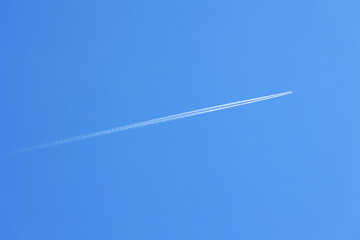 Smuga spalin zostaje za niebem za lecącym samolotem.