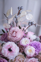 Light gray concrete planter with flowers. Gently pink anemones, pink roses and cream peonies with eucalyptus. Composition on a marble table. Floristics preserved flowers.