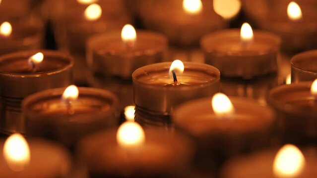 Many small burning candles on a black background