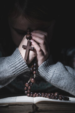 Prayer to God. Portrait of young girl pray with rosary and reading the Bible. Vertical image.