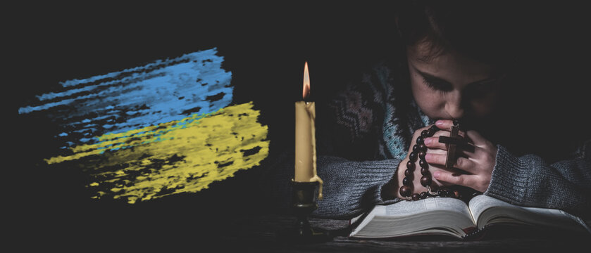 Pray for Ukraine. Save Ukraine from Russia. Young girl pray with rosary and reading the Bible. - Powered by Adobe