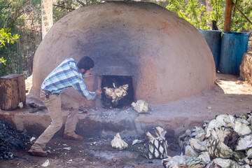 Hombres llenando de piñas de agave el horno de adobe, para preparar raicilla, en san gregorio,...