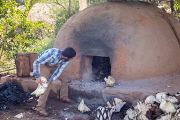 Hombres llenando de piñas de agave el horno de adobe, para preparar raicilla, en san gregorio,...
