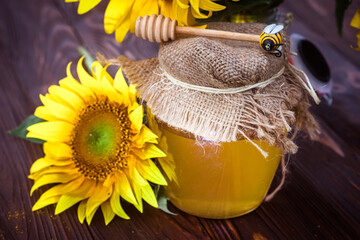 Organic sunflower honey in a transparent jar with a canvas lid and a spoon for honey. Sunflower grown to collect useful healthy honey used in medicine