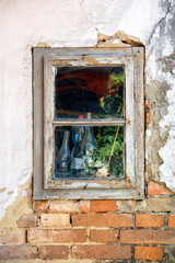 Fototapeta na wymiar Old wooden window and crumbling plaster on a brick wall in a village cottage