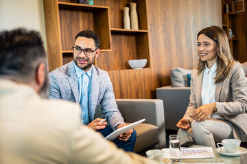 Fototapeta premium Teamwork. Team discussing something and smiling while sitting at the modern business lounge.