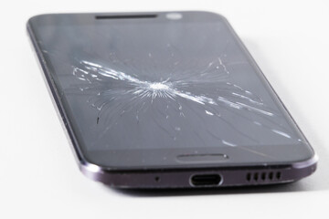 Smartphone with a torn screen on a white table. Cracked display
