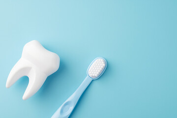 Teeth care and dental hygiene. Toy tooth and toothbrush on blue background, flat lay. Dental concept