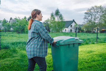 Plastic pollution problem. European 20s girl take out the trash can sorting garbage near a home. Put trash in garbage containers. Volunteers and responsible society.