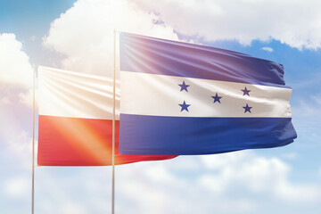 Sunny blue sky and flags of honduras and poland