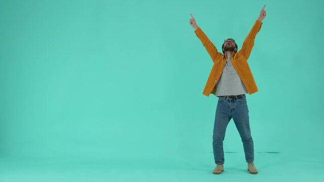 Joyful bearded man showing wow and yes gestures of victory, expressing success in achieved results, goals. Happy guy rejoicing at victory isolated against blue studio background