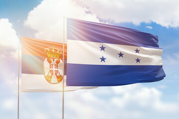 Sunny blue sky and flags of honduras and serbia