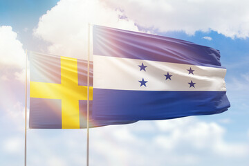 Sunny blue sky and flags of honduras and sweden