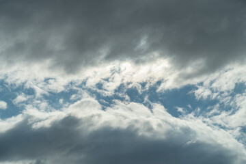 Dark clouds of thunderstorm rain clouds with a gap where the sun shines viewed from below as a...