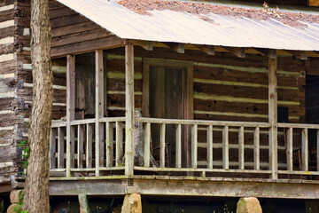 A porch on an old log cabin with a tin roof.