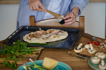 A young pretty woman prepares pizza in the kitchen