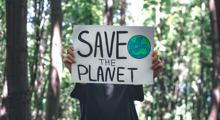 Poster in the call to save the planet in female hands in the forest.