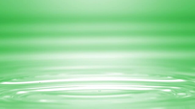 Drop of green fluid falls down on green clear fluid surface creating concentric circles on it on green background | Abstract skin moisturizer formulation concept