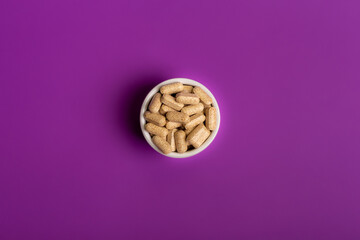 Tablet vitamins in jars on a purple violet background from above. 