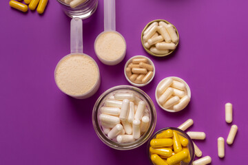 Nutritional supplements and organic vitamins and minerals in jars on violet purple background from above. Food supplements to support human health and immune system.