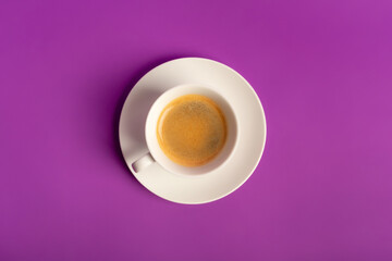 Minimalist food composition with morning aromatic americano coffee with foam on violet purple background from above. 