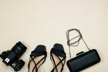 pair of black female heel sandals and handbag or clutch with camera on pink background