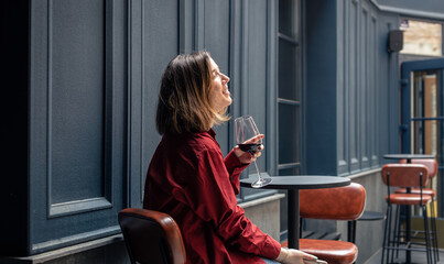 A young woman with a glass of wine on the terrace of a restaurant.